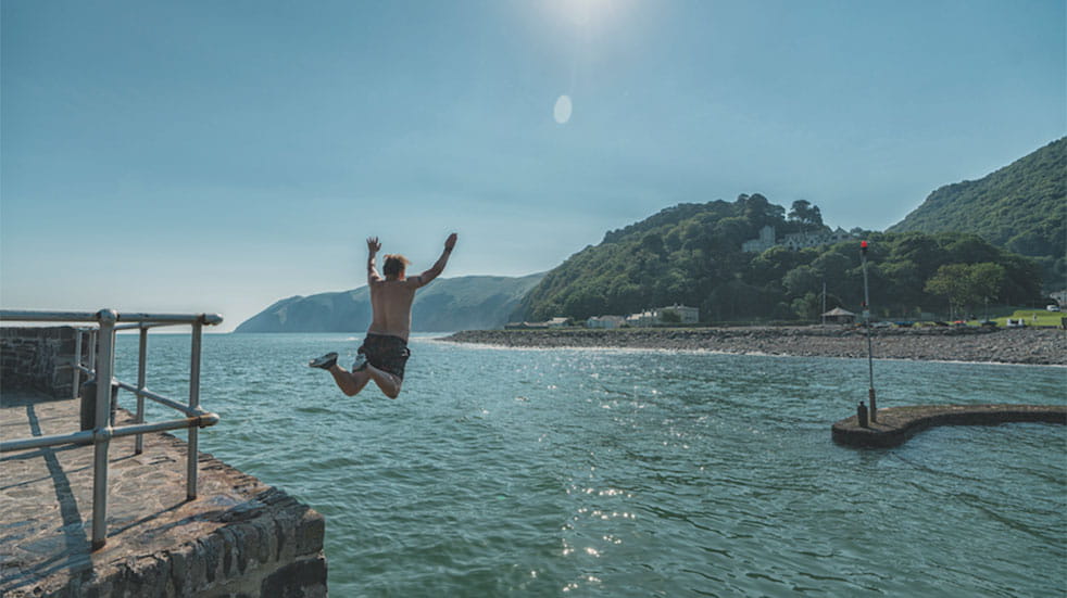 Classic Mini road trip man diving into water